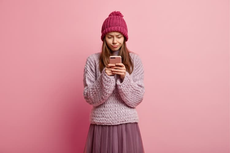 A girl wearing a hat and a tulle skirt is posing for photos with her cell phone.