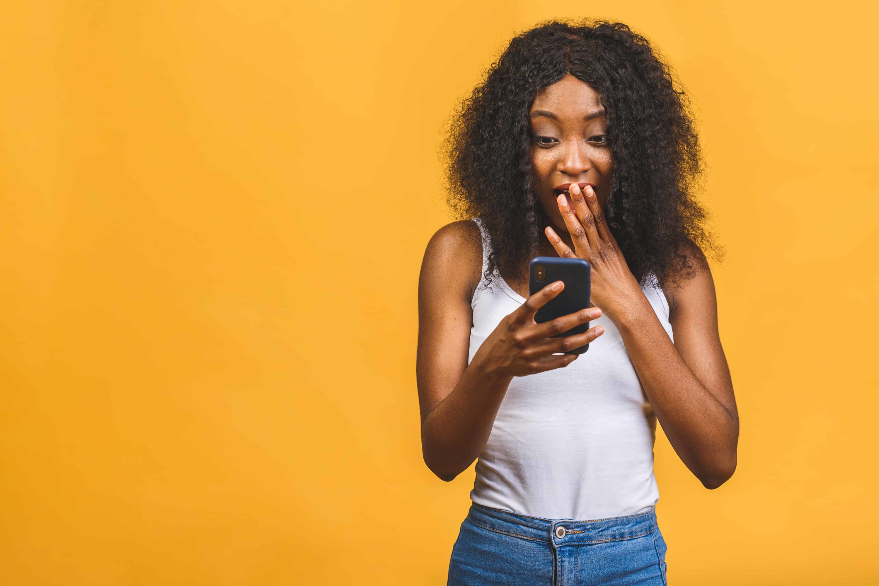 In this Ultimate Guide, a young black woman is seen glancing at her phone with her mouth open.