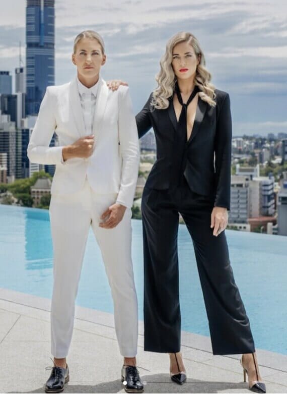 Two women in suits standing next to a pool for a Mobile Tailor event.