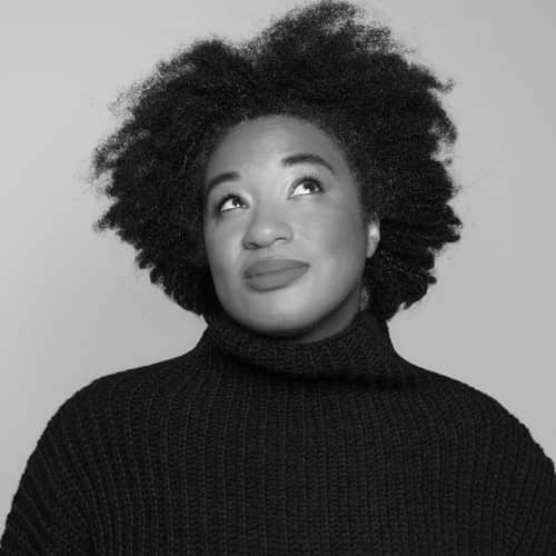 A black and white photo of a woman with afro hair, showcasing her unique style as an influencer.