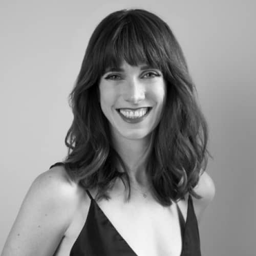 A black and white photo of a smiling woman, showcasing sustainable fashion.