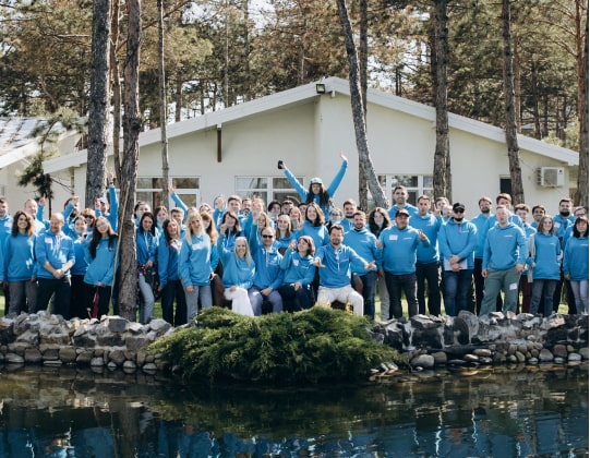 A group of individuals in blue shirts posing by a pond.