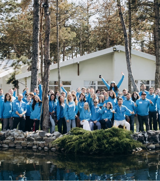 A group of people in blue shirts standing in front of a pond during their careers.