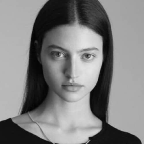A black and white photo of a woman wearing a necklace, featuring sustainable fashion.