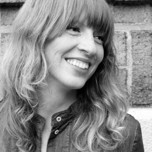 A black and white photo of a woman smiling, showcasing sustainable fashion.