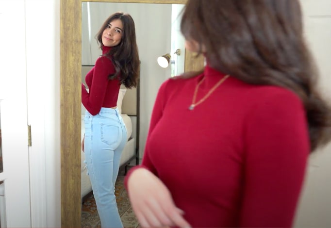 An influencer stands in front of a mirror, showcasing sustainable fashion.