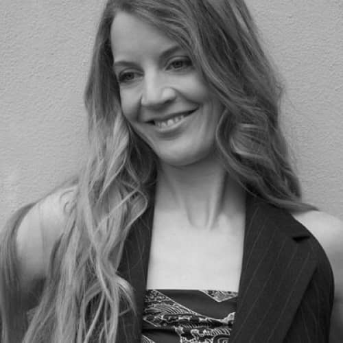 A black and white photo of a woman smiling, showcasing the top influencers in sustainable fashion.