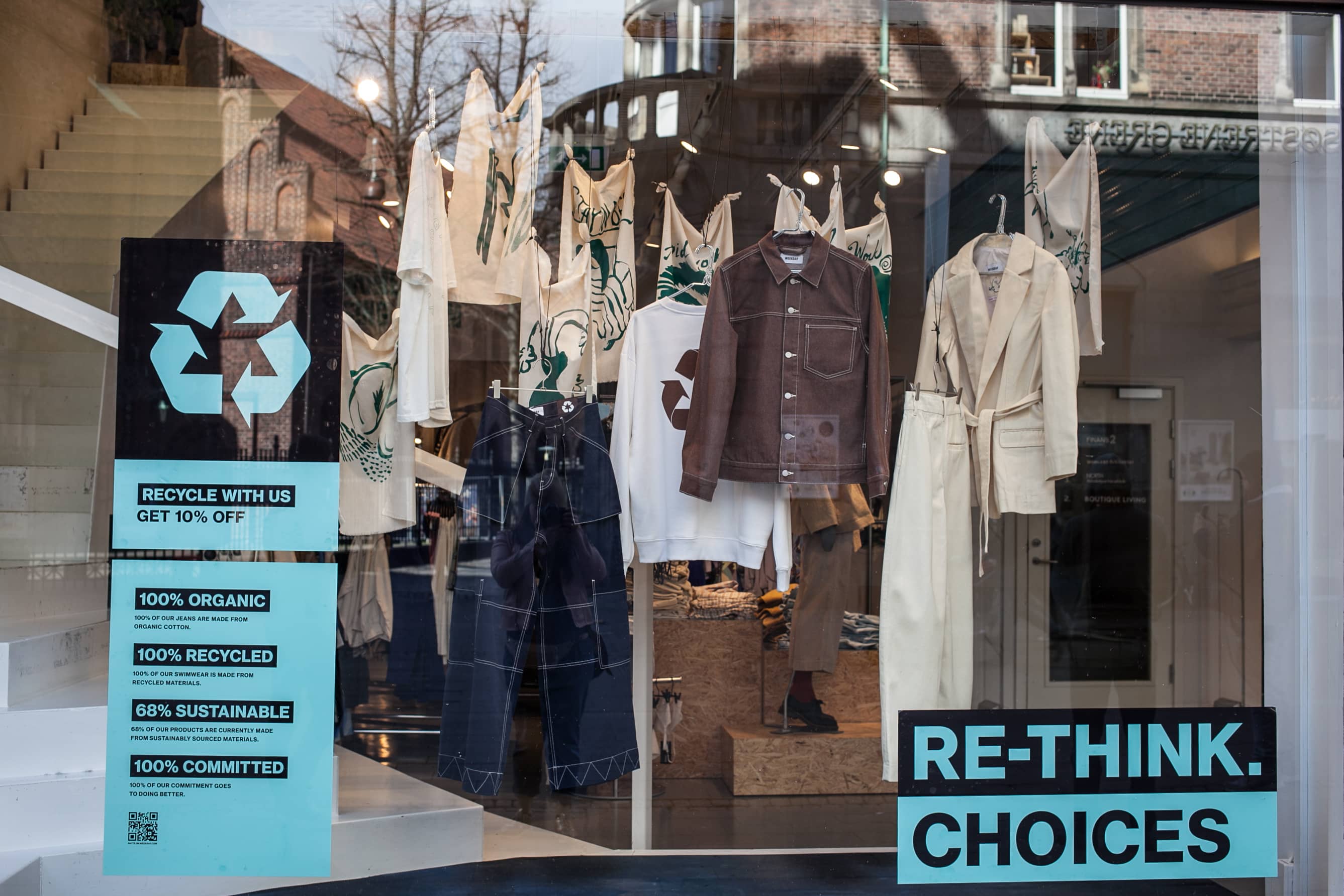 A store window with a sign encouraging customers to rethink their choices in sustainable fashion.