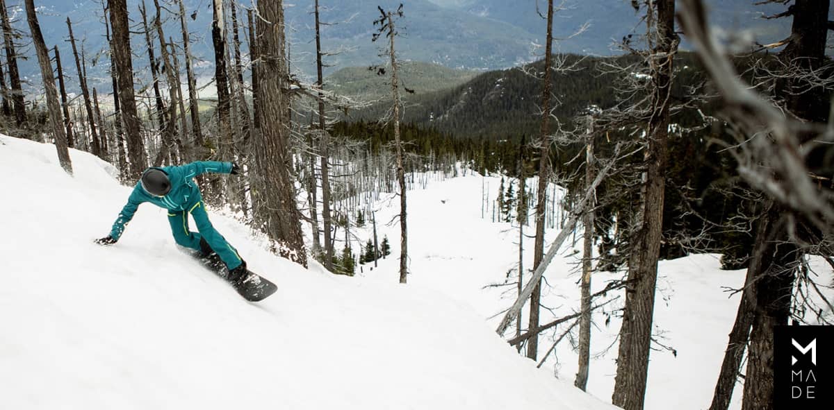 A snowboarder is riding down a snowy slope in the great outdoors.