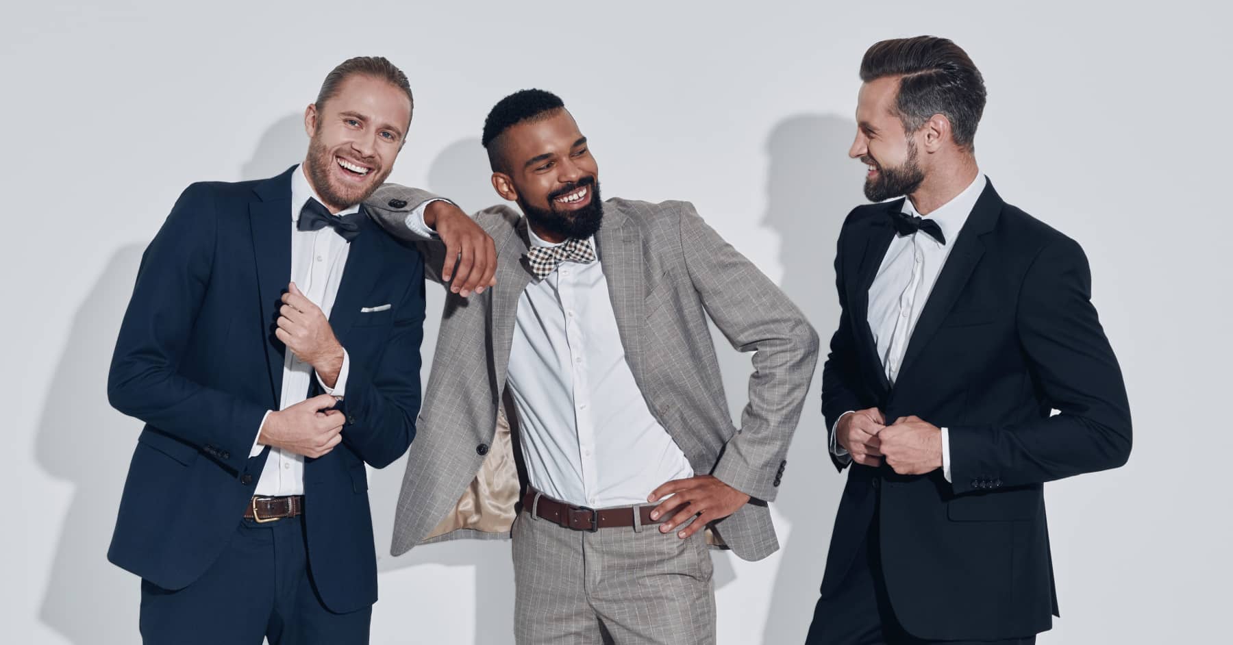 Three men in tuxedos posing for a photo at a Country Vogue Boutique.
