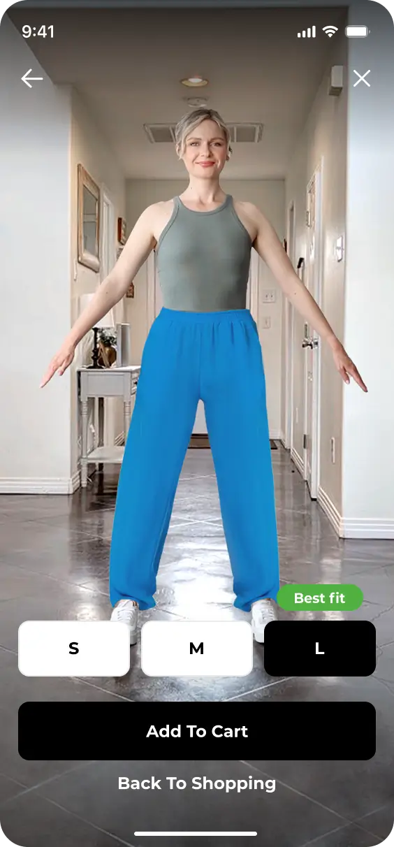 A person stands in a hallway modeling blue pants and a gray tank top. The screen, redesigned with the YourFit feature, displays size options (S, M, L), highlights "Best fit" on L, and provides buttons for "Add to Cart" and "Back to Shopping.
