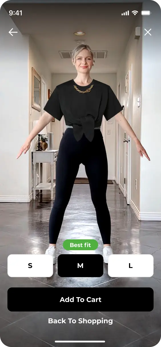 A person is standing in a hallway, modeling a black t-shirt and black pants with their arms outstretched. The image illustrates the new 2024 redesign featuring YourFit technology, offering size options S, M, and L. "Add To Cart" and "Back To Shopping" buttons are shown below.