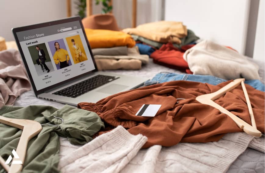 On a bed adorned with folded clothes and a credit card, a laptop displays a fashion store website. It's the perfect balance of style meeting health-conscious shopping, echoing the precision of breakthrough innovations like GLP-1 market trends.