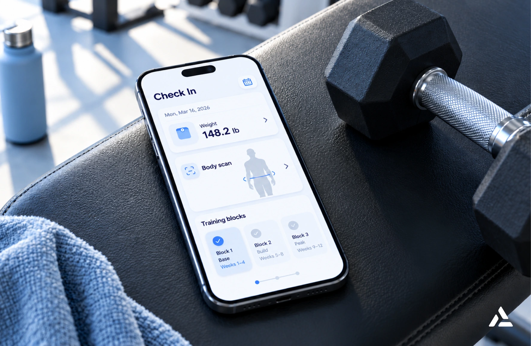 A smartphone on a gym bench displaying a fitness tracking app with body scan, weight loss tracking, and training block information.